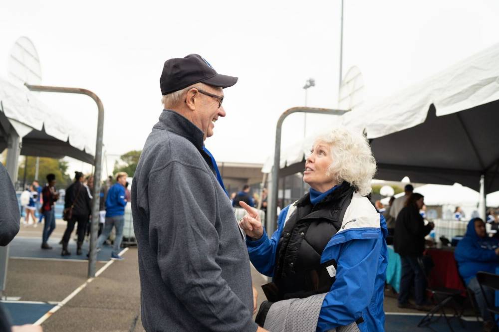 An alumni from the class of '68 enjoys conversation with Marcia Haas at the Alumni Homecoming Tailgate.